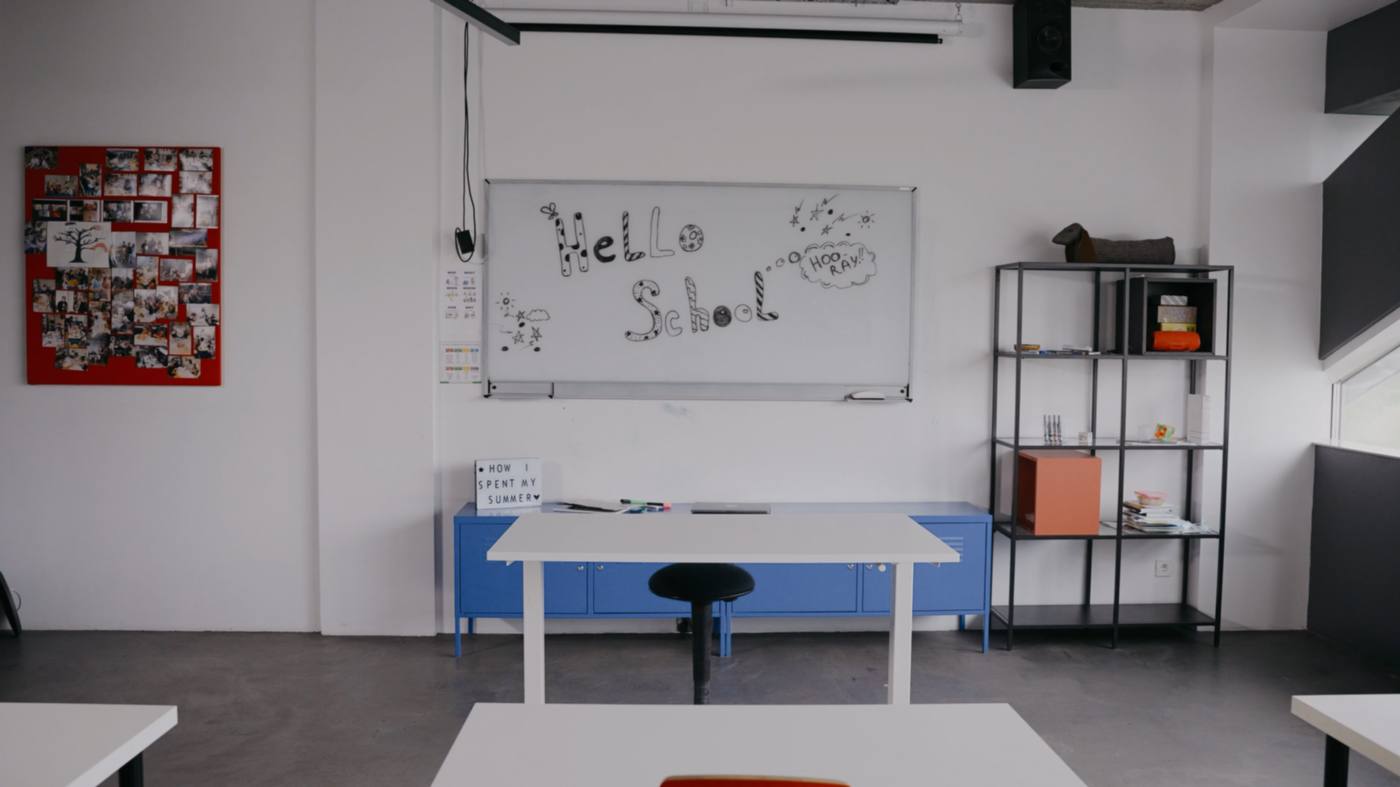 An empty classroom set out and ready before the school day, chairs pushed in and the board wiped clean